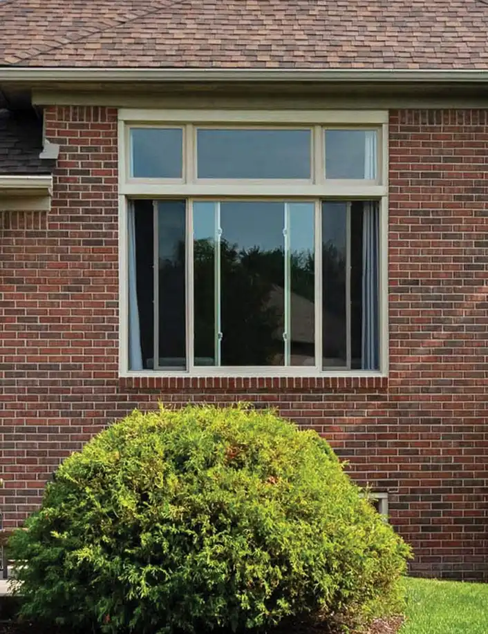 Exterior view of an opened Marvin Replacement Slider window on a brown brick home backyard.