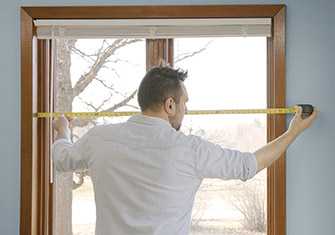 man-measures-window-frame-with-tape-measure