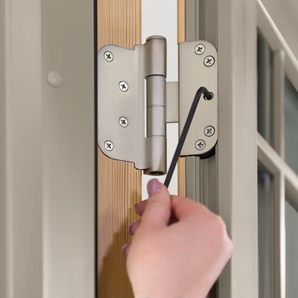 A women uses an Allen wrench to adjust a French door hinge.