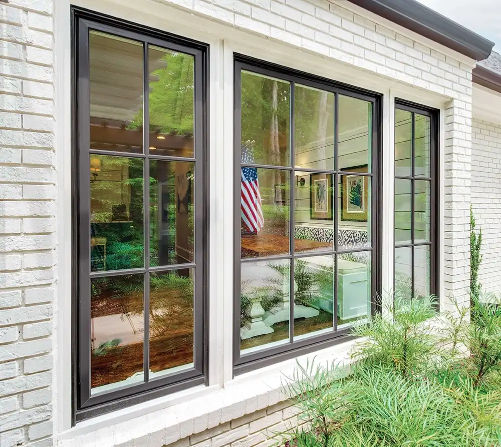 Exterior view of brown casement windows with divided lites on a white brick home
