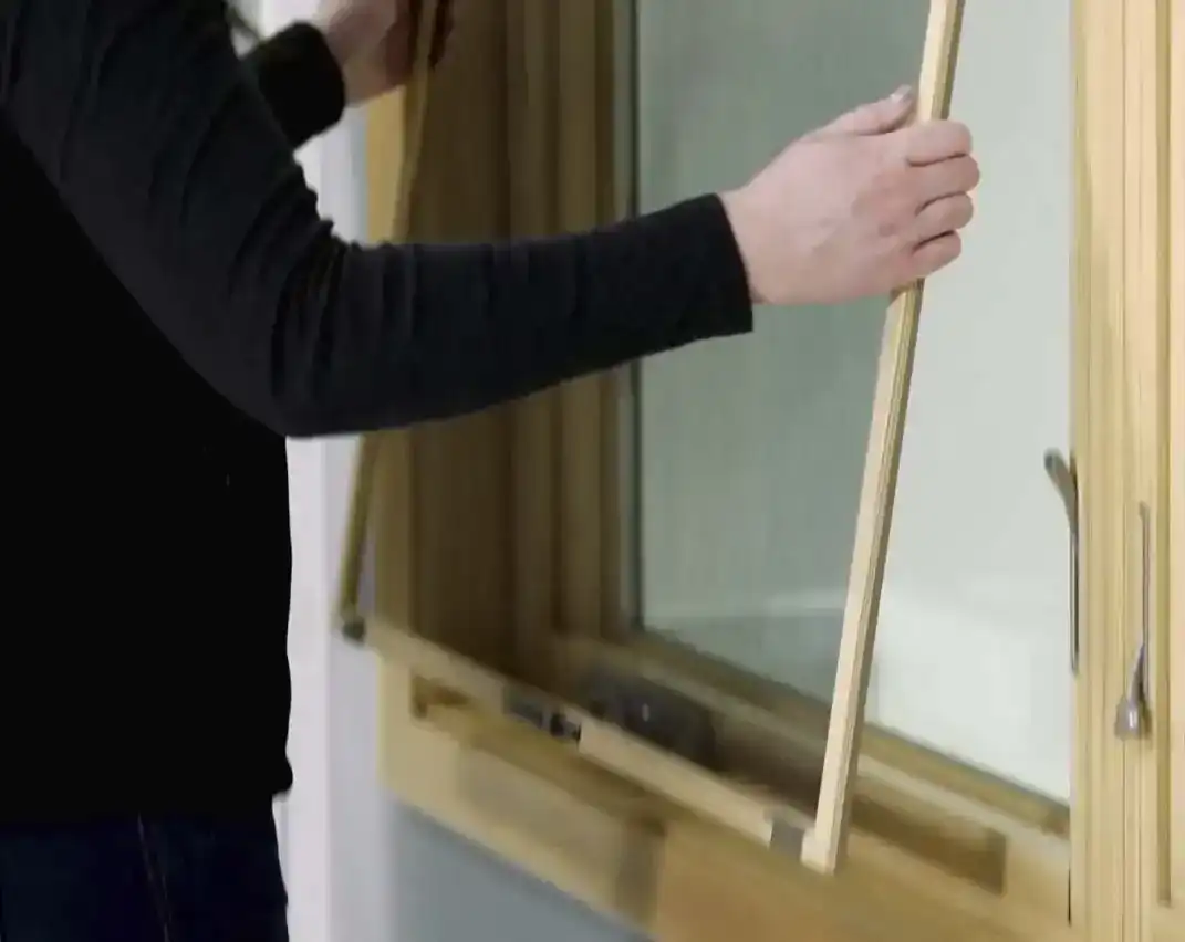 Woman holds window screen in both hands as she removes it.