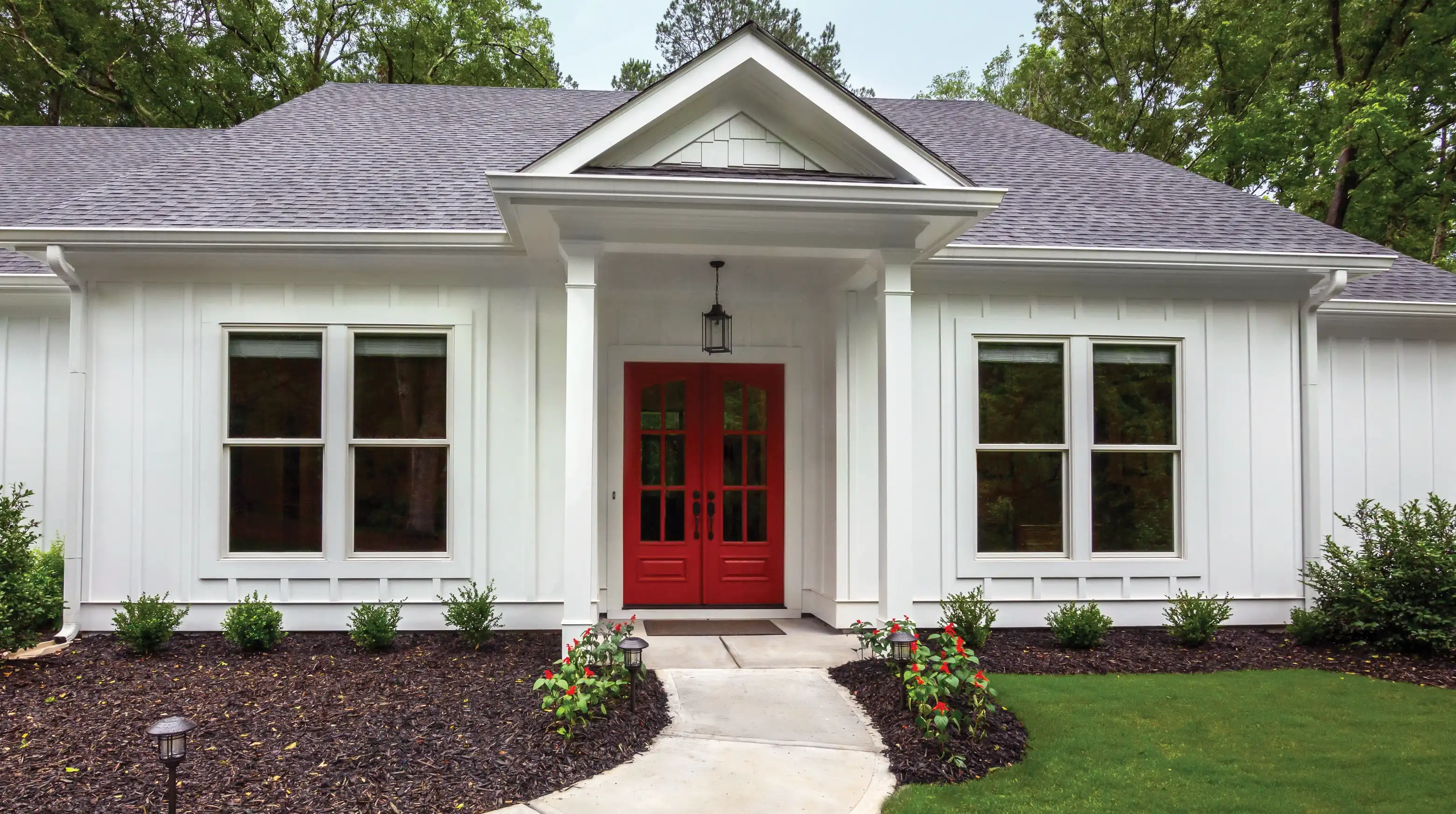 Exterior view of Marvin Replacement Double Hung windows on a white house with a red front door.