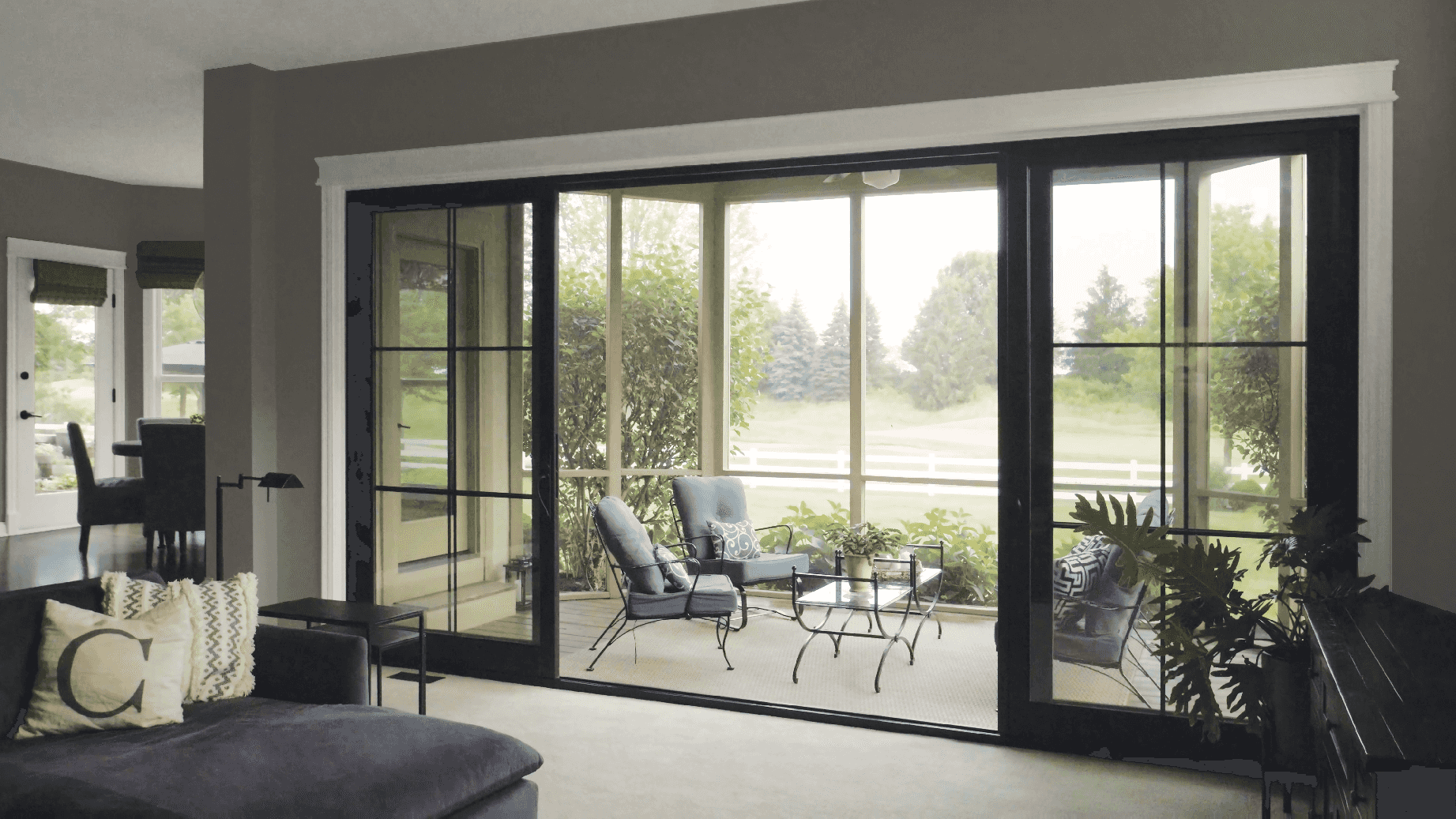 Interior living room and porch image featuring an Infinity Sliding French Door in Ebony interior finish with Matte Black hardware.
