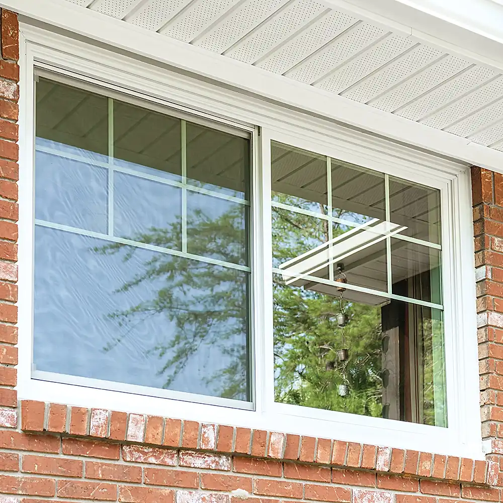 Exterior view of a white Marvin Replacement slider window with grilles on a brick home.