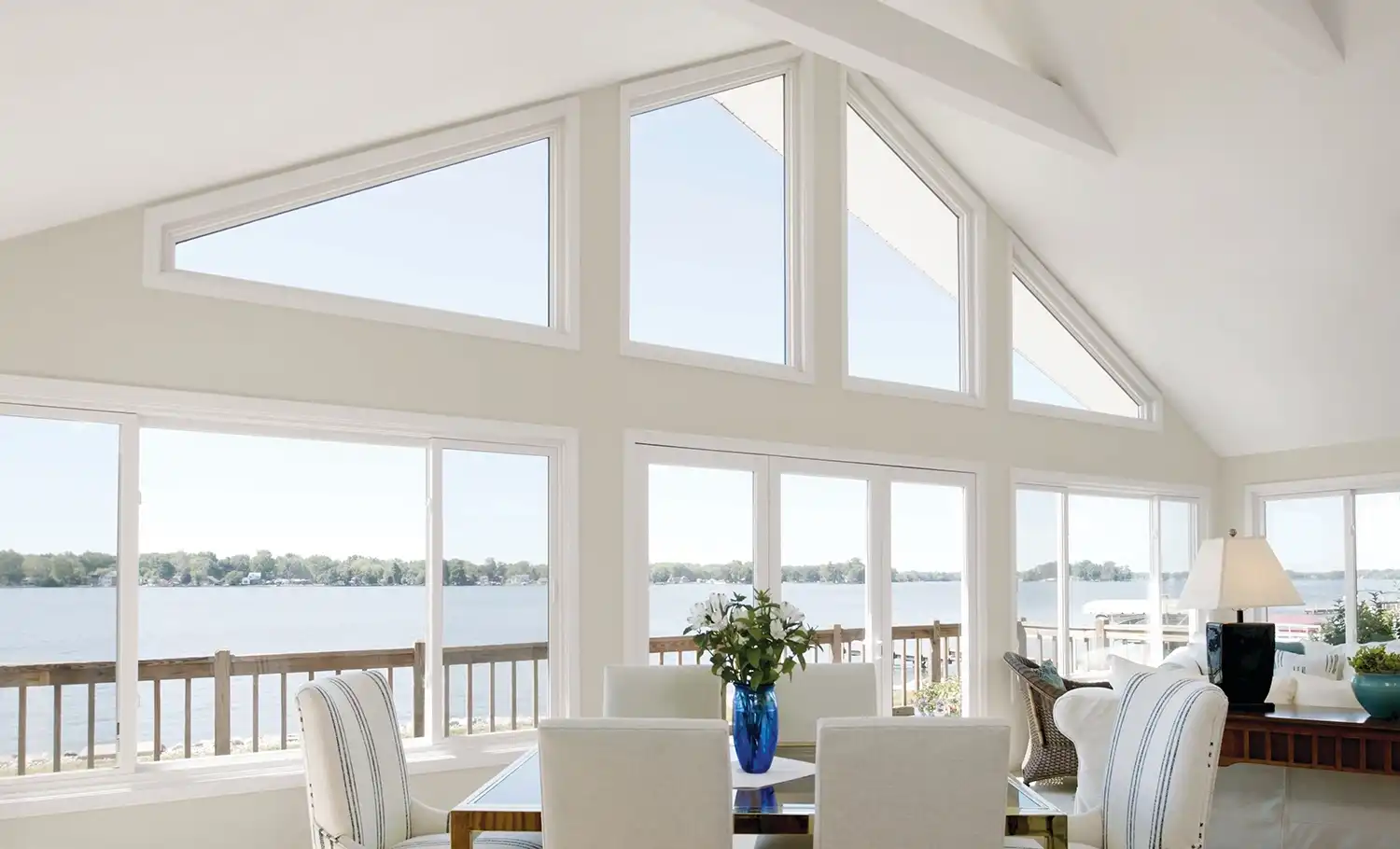 Interior view of a living room featuring white Marvin Replacement windows overlooking a lake.