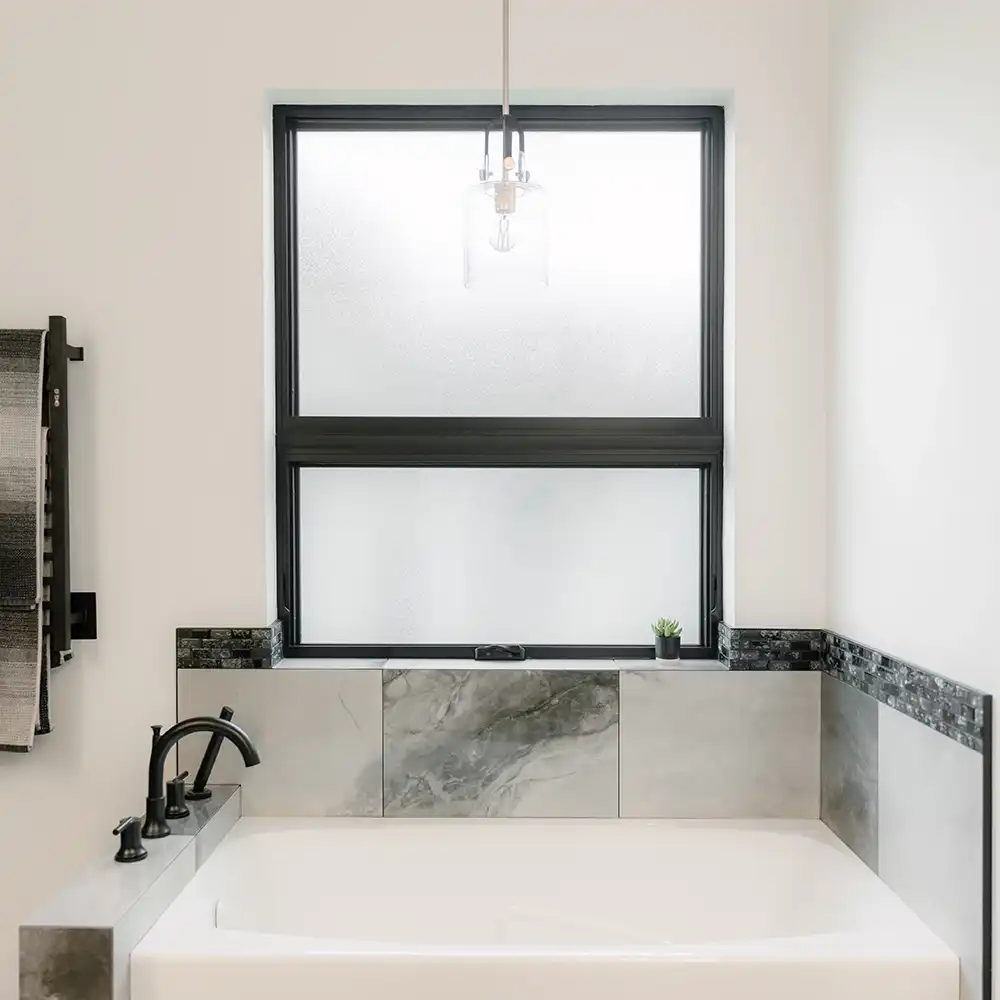 Interior view of a black awning window above a bathroom tub.