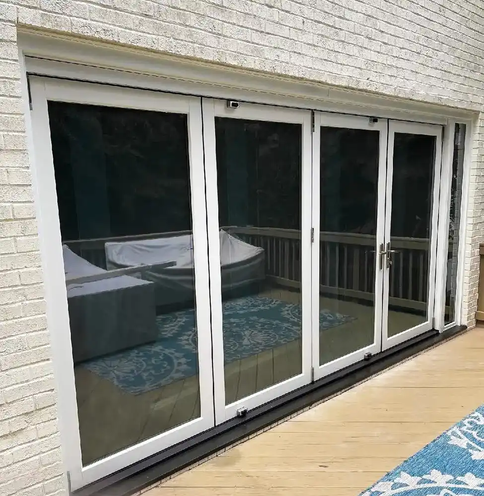 Exterior view of an installed Marvin Replacement four-panel bi-fold door with an access panel on a patio.