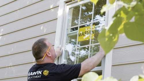 A man installation a Marvin Replacement window from the exterior of a home.
