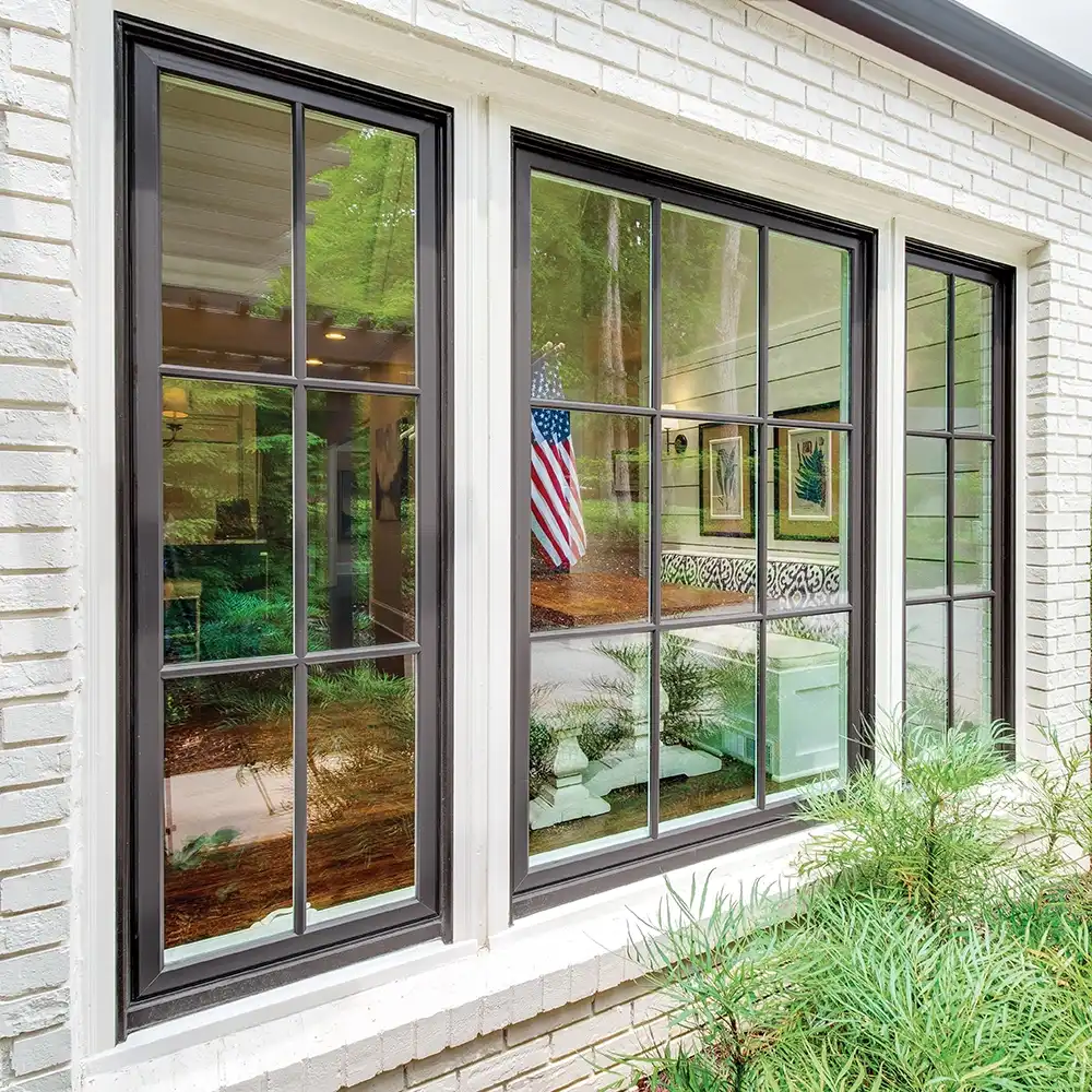 Exterior view of casement windows with window grilles on a white brick home.