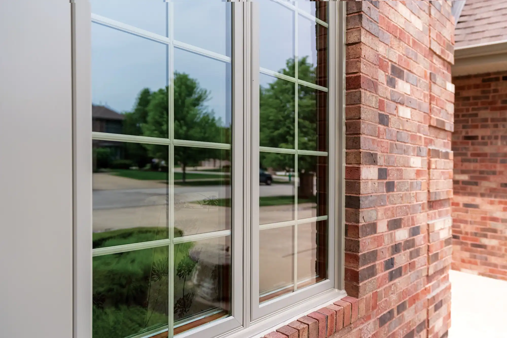 Exterior view of a light brown Marvin Replacement window with divided lites on an brick home.