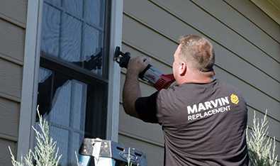 Man uses a reciprocating saw to cut a window frame