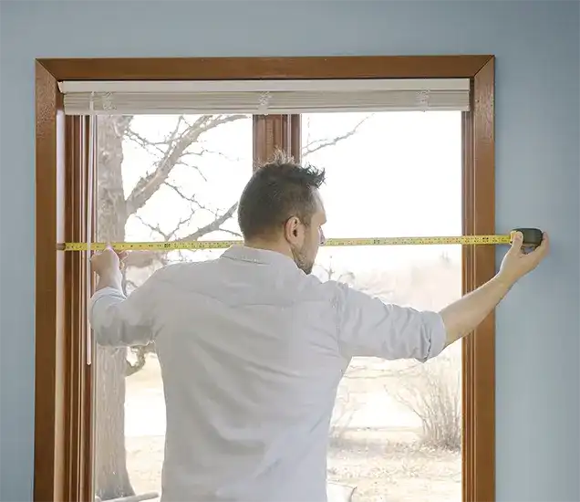 Man measures window frame with tape measure