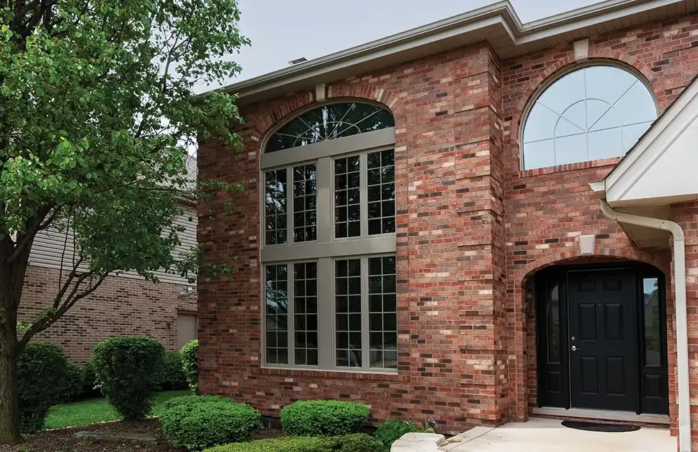 Exterior view of a brick home with Marvin Replacement Round Top windows
