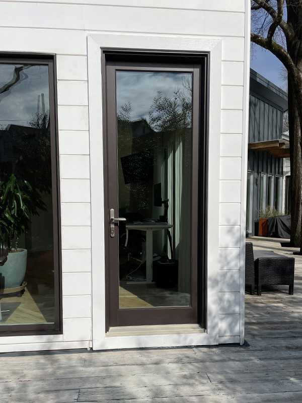 Exterior view of a black Marvin Replacement Inswing French door installed on a patio.
